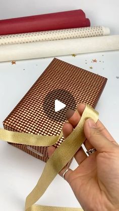 a person is holding a gold ribbon in front of a box with a video on it