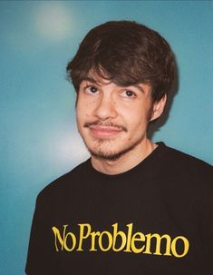 a man wearing a no problemo t - shirt in front of a blue background