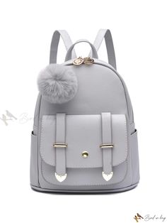 a gray backpack with pom - pom on the front and two handles,