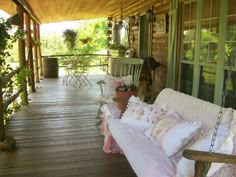 a porch covered in lots of pillows and furniture