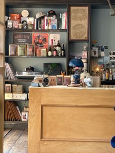 the front desk of a store with many items on shelves and bookshelves behind it