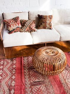 a white couch sitting on top of a wooden floor next to a red and black rug