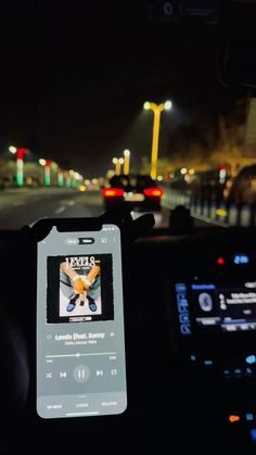 an electronic device is sitting in the dashboard of a car at night with traffic lights behind it