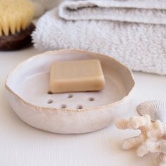 a white dish with soap on it next to some seashells