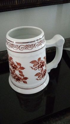 a white and red coffee mug sitting on top of a counter next to a mirror