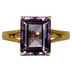 Make an instant statement with this pre-loved 9k yellow gold ring featuring a striking natural emerald-cut amethyst. This ring effortlessly combines boldness with minimalist sophistication, ideal for anyone who loves a standout piece without compromising on elegance. The deep purple hue of the amethyst is perfectly accentuated by the sleek emerald cut, creating a timeless design. Originating from England and stamped for authenticity, this ring is ready to be worn and adored once more. Materials: Purple Hues, Yellow Gold Ring, Natural Emerald, Amethyst Ring, Yellow Gold Rings, Solitaire Ring, Emerald Cut, Deep Purple, Gold Ring