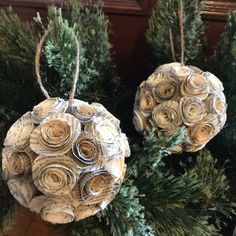 two ornaments made out of old book pages are hanging from the branches of a christmas tree