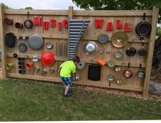 a young boy playing in front of a music wall made out of pots and pans