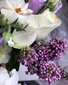 white and purple flowers are in a vase