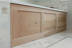 a bathroom with white tile and wooden doors on the wall, along with marble flooring