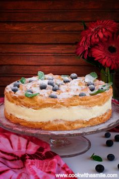 a cake sitting on top of a glass platter next to red and white flowers