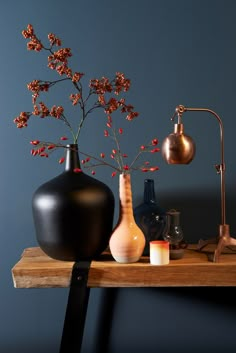 two vases with flowers on a table in front of a blue wall and an orange color scheme