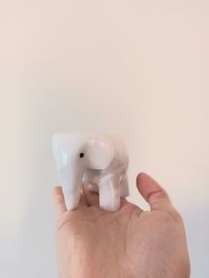 a hand holding a small white elephant figurine