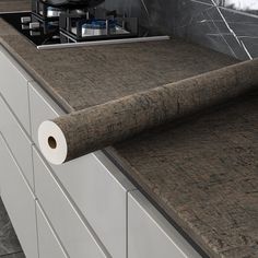 a roll of paper is on the counter top next to a stove and cabinets in a kitchen