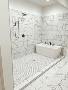 a large bathroom with white marble tile walls and floor, along with a walk in shower