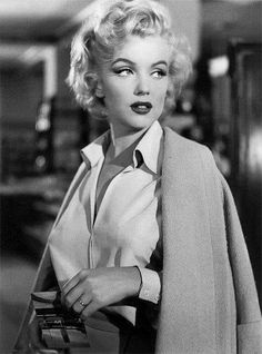 a black and white photo of a woman with blonde hair wearing a jacket and tie