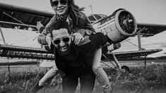 a man carrying a woman on his back in front of an airplane