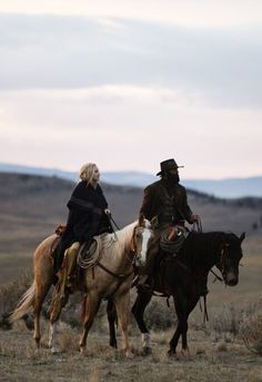 two people riding horses in an open field