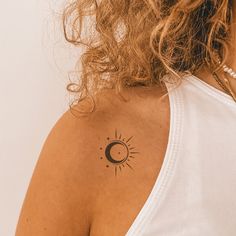 a woman with a sun and moon tattoo on her upper arm, behind her left shoulder