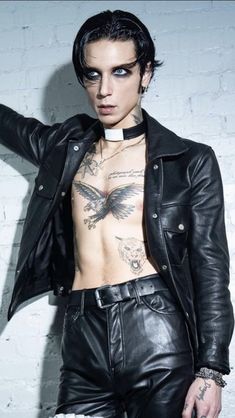 a shirtless man wearing leather pants and a black jacket with tattoos on his chest