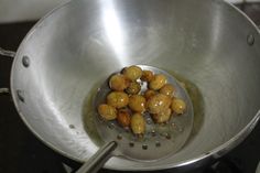 some food is being cooked in a large metal bowl on the stove top with tongs