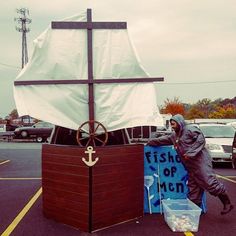 a man standing in front of a boat with a sign on it's side