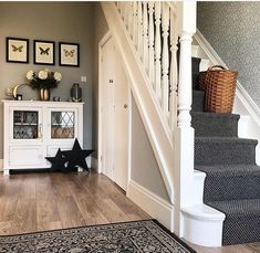 a stair case next to some stairs with pictures on the wall and rug below it