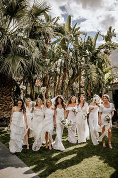 a group of bridesmaids in white dresses and bouquets walking through the grass