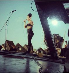 a woman standing on top of a stage with microphones in front of an audience