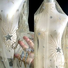 two mannequins covered in sheer fabric with gold and silver stars on them