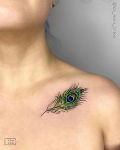 a woman's chest with a peacock feather tattoo on it