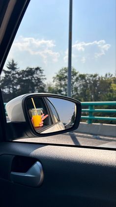 a side view mirror on the back of a car with a yellow drink in it