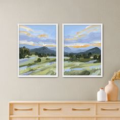 two paintings on the wall above a dresser with vases and flowers in front of it