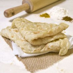 three pita breads sitting on top of a table next to a rolling pin