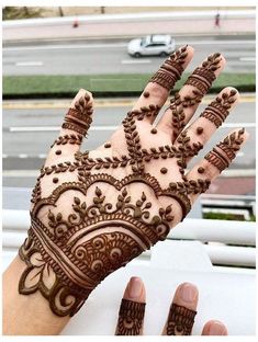 a henna on someone's hand with cars in the background