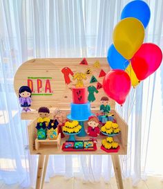 a birthday party with balloons and decorations on a wooden table in front of a window