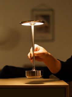 a person sitting at a table with a lamp on it's head and one hand holding the base