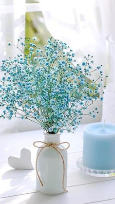 blue flowers in a vase next to a candle