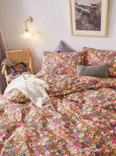 a bed covered in colorful floral sheets and pillows