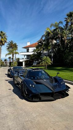 three black sports cars parked in front of a house with palm trees on the side