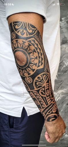 a man's arm with an intricate tattoo design on the left forearm and shoulder