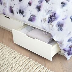 a bed with two drawers underneath it on the floor next to a rug and carpet