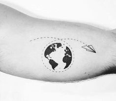 a black and white photo of a person's arm with an airplane flying around the earth