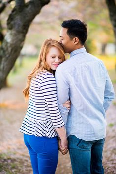 a man and woman standing next to each other under trees