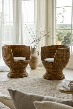 two wicker chairs sitting on top of a rug next to a vase and window