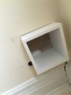 a white toilet sitting in a bathroom next to a wall mounted box on the side of a wall