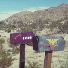 two mailboxes in the desert with mountains in the background