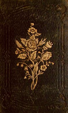 an old book with gold flowers and leaves on the cover, sitting on a table