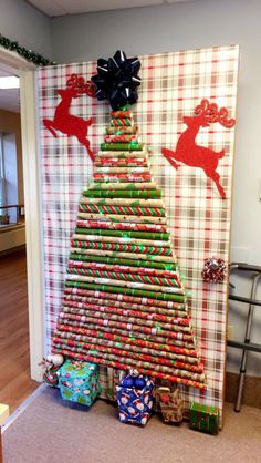 a christmas tree made out of rolled up wrapping paper with presents under it and reindeers on the wall