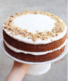 a person holding a cake on top of a white plate with frosting and crumbs